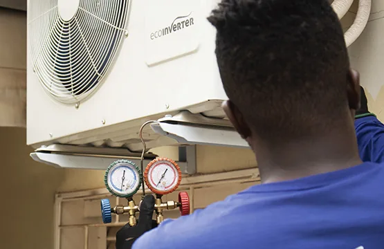 Técnico da Conect Ar operando o manifold de manômetros acoplado à condensadora de um ar-condicionado inverter